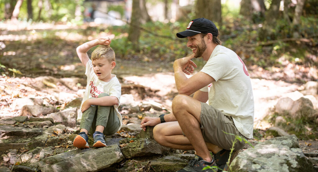 Dad and son, father son bonding sitting by creek, abundant living